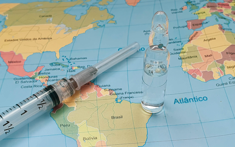 vaccine and injection vial on the world map 